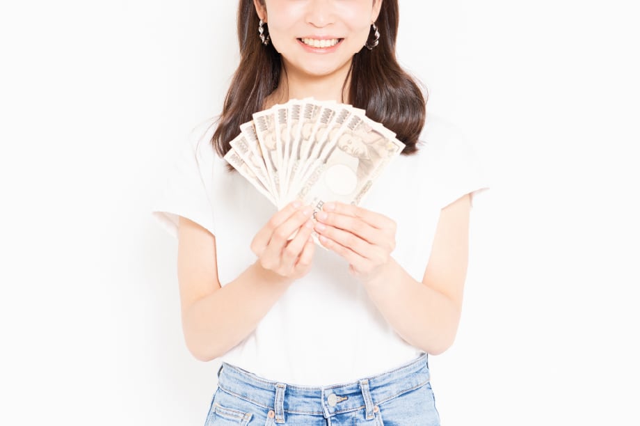 10万円を両手で持つ笑顔の女性